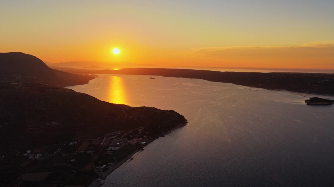 Vista aérea de drone de uma ampla baía e estância balnear costeira abaixo de um longo promontório ao pôr do sol, Chania, Grécia.
