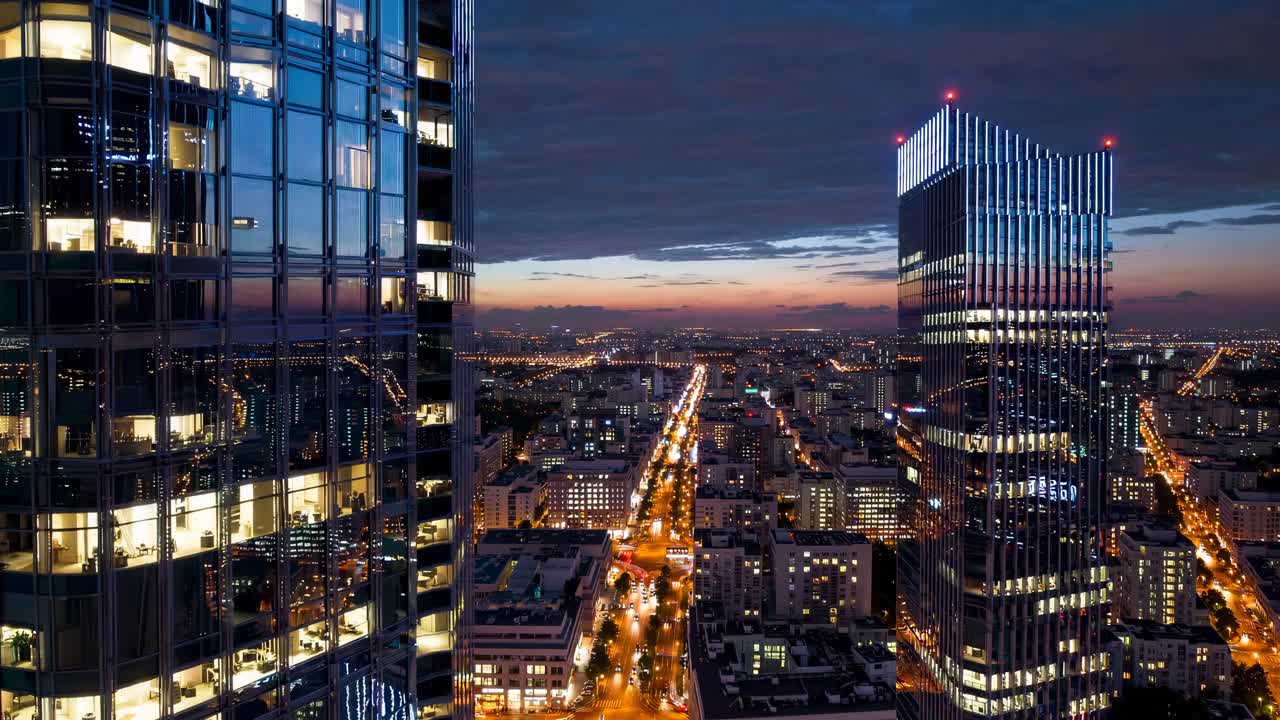 Aerial video view of a cityscape at dusk, showcasing illuminated skyscrapers and bustling streets