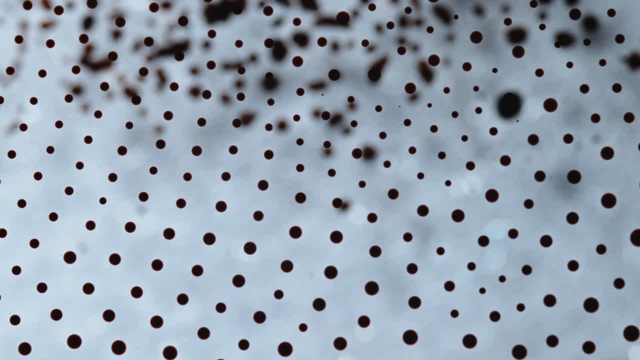 Primo piano dell'inchiostro che si mescola con un intricato motivo a punti, inquadratura macro.