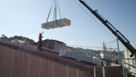 worker at a construction roof directing a load to be downloaded
