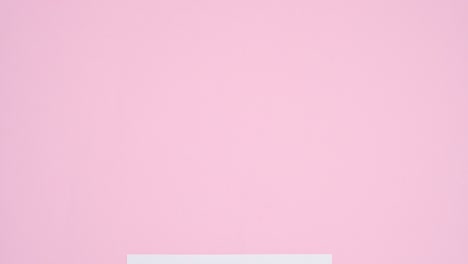 little cute pink heart balloons appear around white paper card note for valentine's day. stop motion flat lay