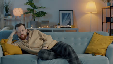 man relaxing on a couch watching tv