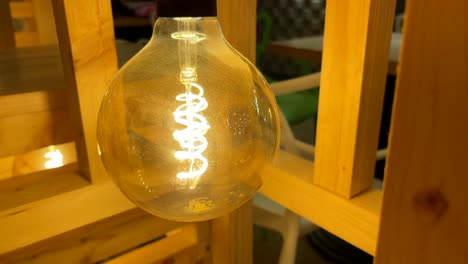close-up of a glowing edison light bulb in a wooden frame