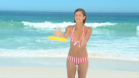 schöne frau spielt frisbee am strand