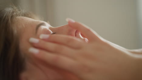 mujer joven golpea la piel con un parche nutritivo con los dedos en una habitación iluminada en cámara lenta. la mujer aplica almohadillas especiales debajo de los ojos para hidratar la piel de la cara