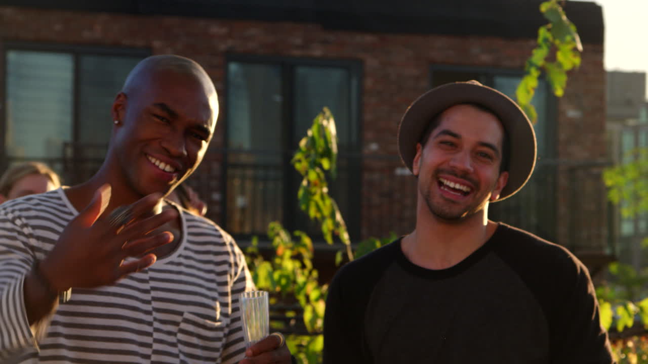 Three male friends gesturing to camera at a rooftop party