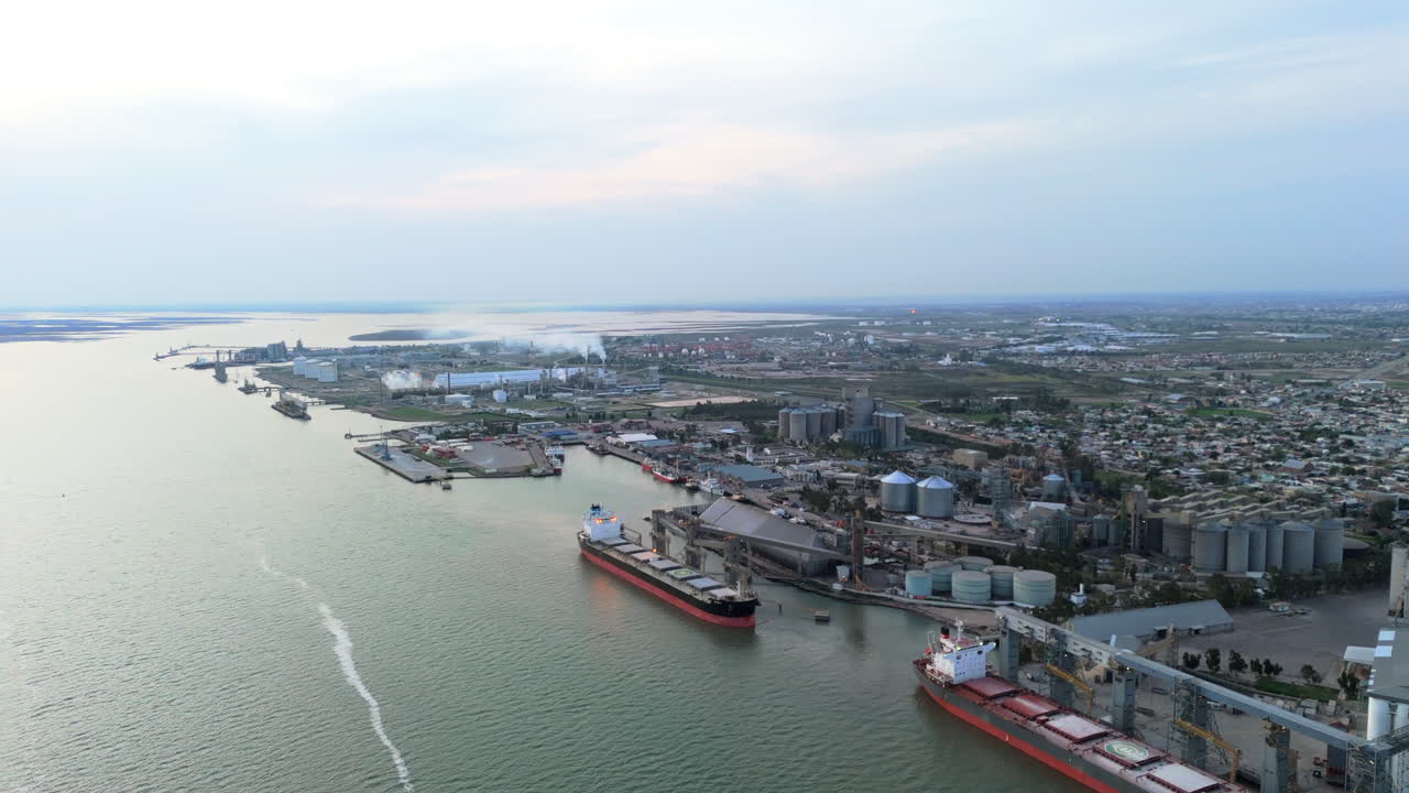 Stunning aerial dolly shot of the port of Bahia Blanca, big ships, industrial buildings, argentina, on a cloudy day, copy space