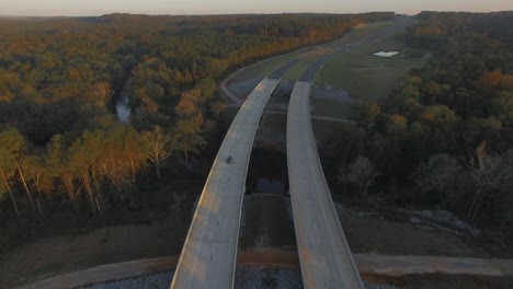 Cars-driving-on-rural-two-lane-road-bridge-over-small-creek