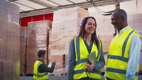 portrait of male and female freight haulage managers with digital tablet by lorry being loaded