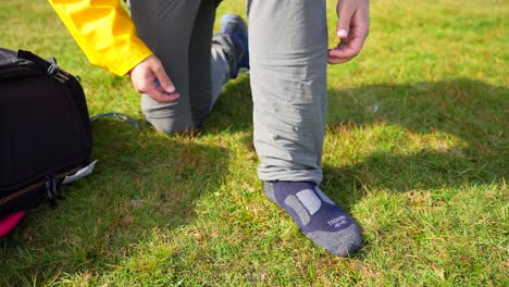 Detail-shot-of-kneeling-man-putting-on-long-trekking-sock,-then-stands-up-and-starts-walking