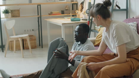 young multiethnic couple checking clothes and speaking at home