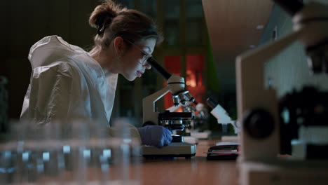 a young beautiful female scientist works with a professional microscope in the laboratory—medium shot