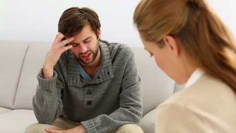 Young-man-sitting-on-sofa-talking-to-his-therapist