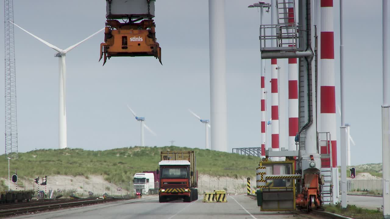 Industrial scene at Rotterdam port with cranes and wind turbines
