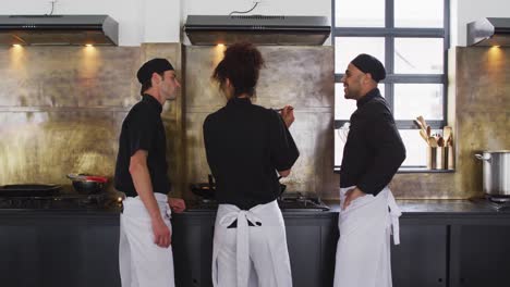 grupo diverso de chefs preparando un plato y sonriendo en una cocina