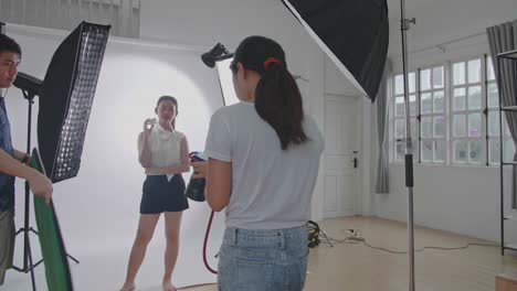 behind the scenes on photo shoot: beautiful asian model poses for a photographer, she takes photos with professional camera