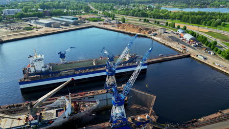 shipyard with cranes, docked ships, and industrial buildings by the water