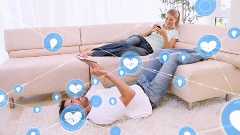 animation of network of connections with icons over caucasian couple using tablet and smartphone