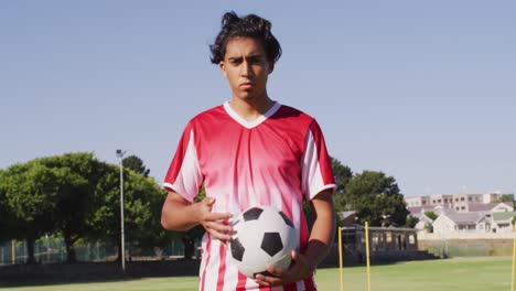 video of diverse male biracial football player standing on field with ball