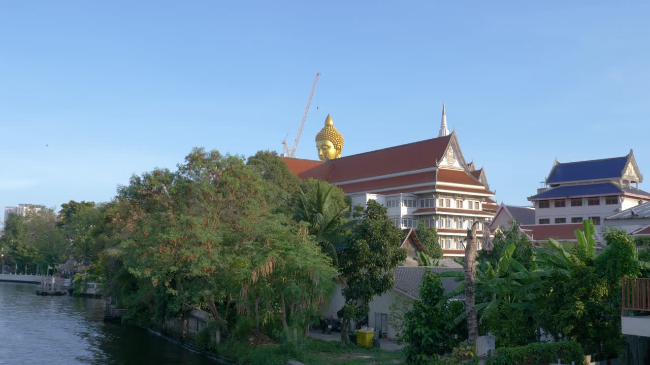 una gran cabeza de buda que se eleva sobre un vecindario en tailandia