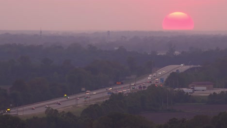 una bola gigante de un sol poniente detrás de una autopista ocupada o tráfico de autopista cerca de memphis tennessee