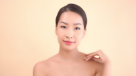 A-close-up-young-beautiful-Asian-woman-strokes-the-skin-on-her-face-and-neck