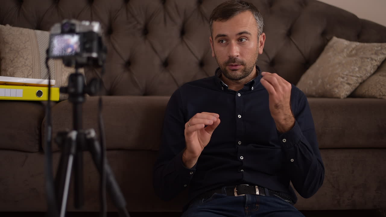Man recording a video blog indoors using camera on tripod