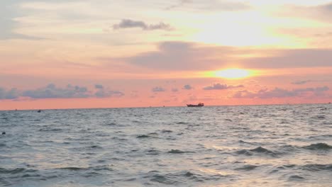 Aerial-drone-shot-following-fishing-boat-floating-alone-in-the-ocean-bay-towards-sunset-in-Phu-Quoc-island,-Vietnam