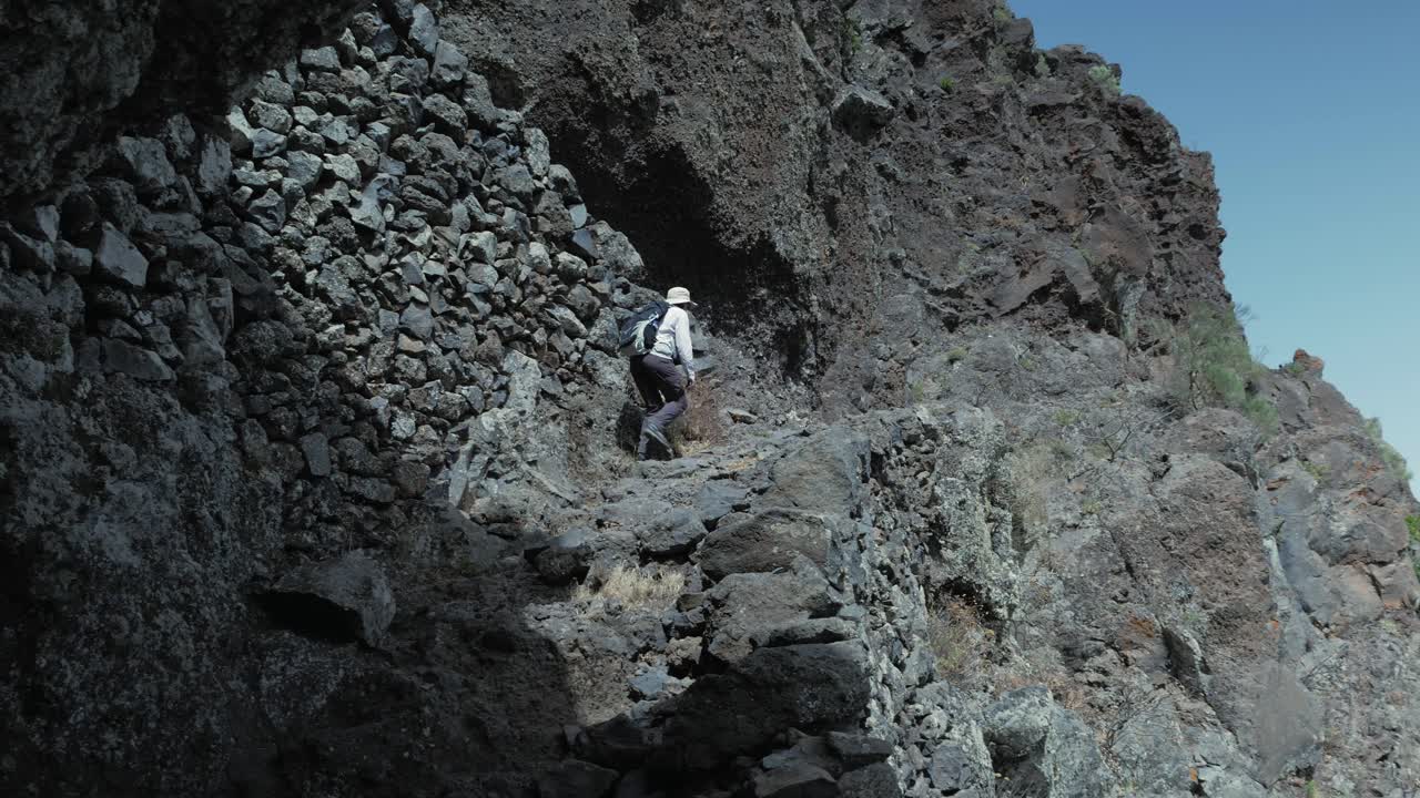 테네리페의 절벽 가장자리에 있는 테노 산맥의 가파른 바위길을 고 있는 여성 하이커