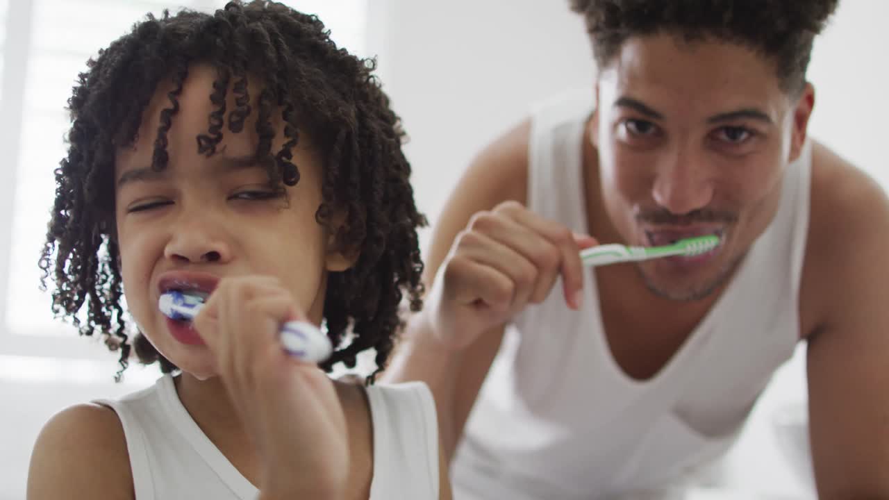 Happy biracial man and his son washing teeth in bathroom