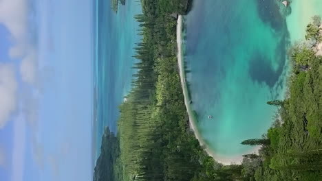 Crystal-clear-waters-and-white-sand-beach-of-Kanumera-Bay-on-the-Isle-of-Pines---ascending-aerial-in-vertical-orientation