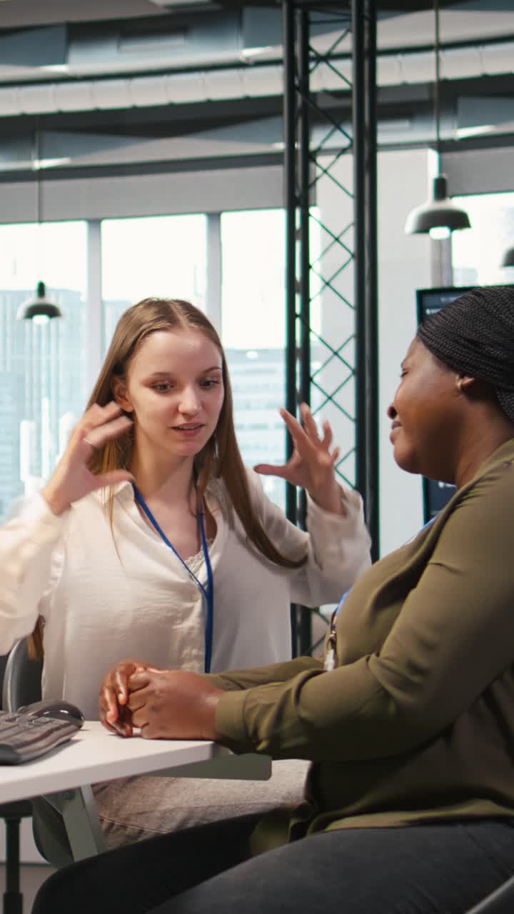 Vertical video Friendly office senior mentor helping stressed intern at work, giving advice