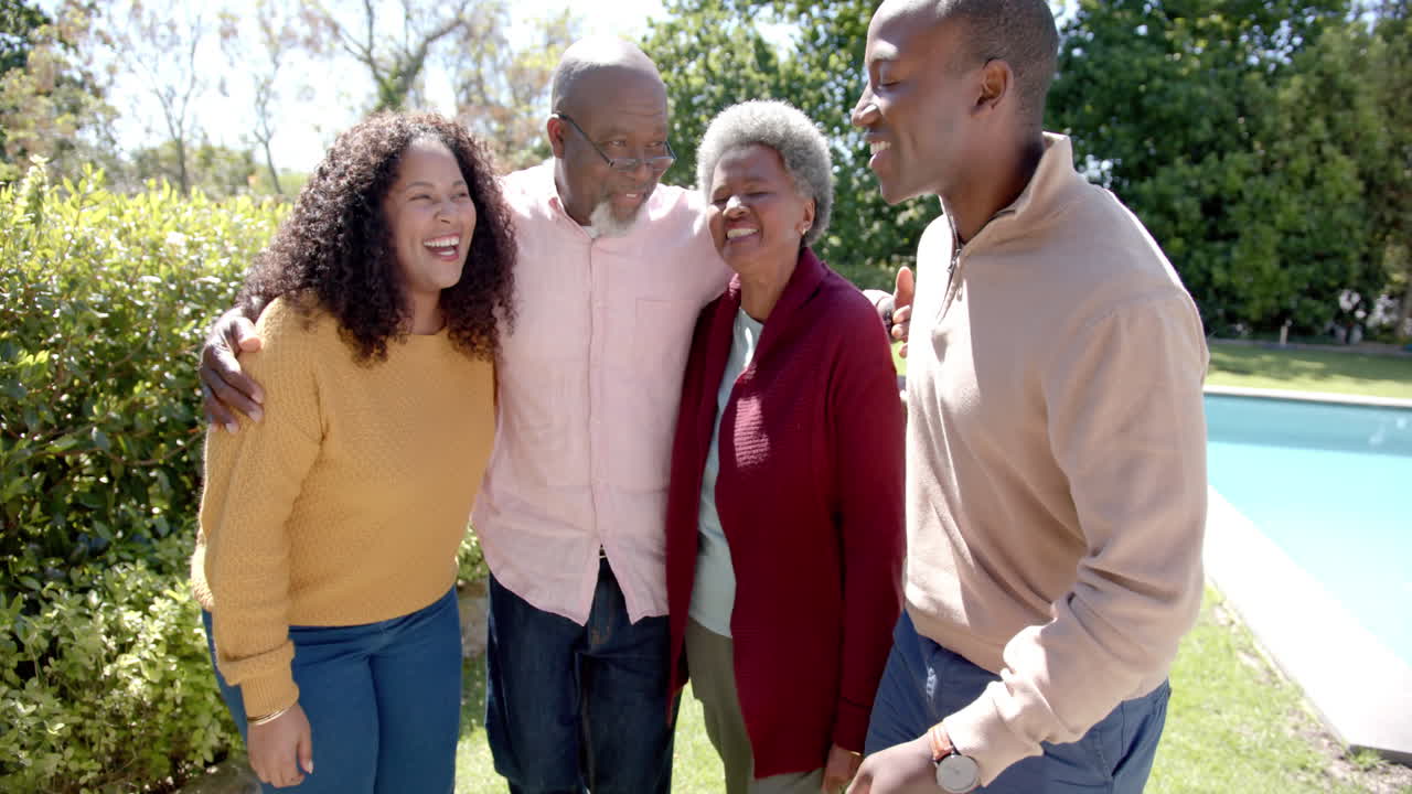 retrato de una feliz pareja afroamericana y padres mayores abrazándose en un jardín soleado