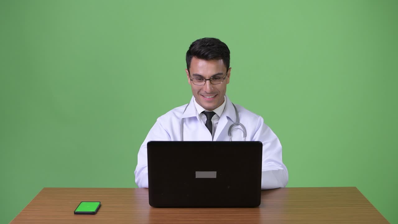 joven hombre hispano guapo médico contra fondo verde