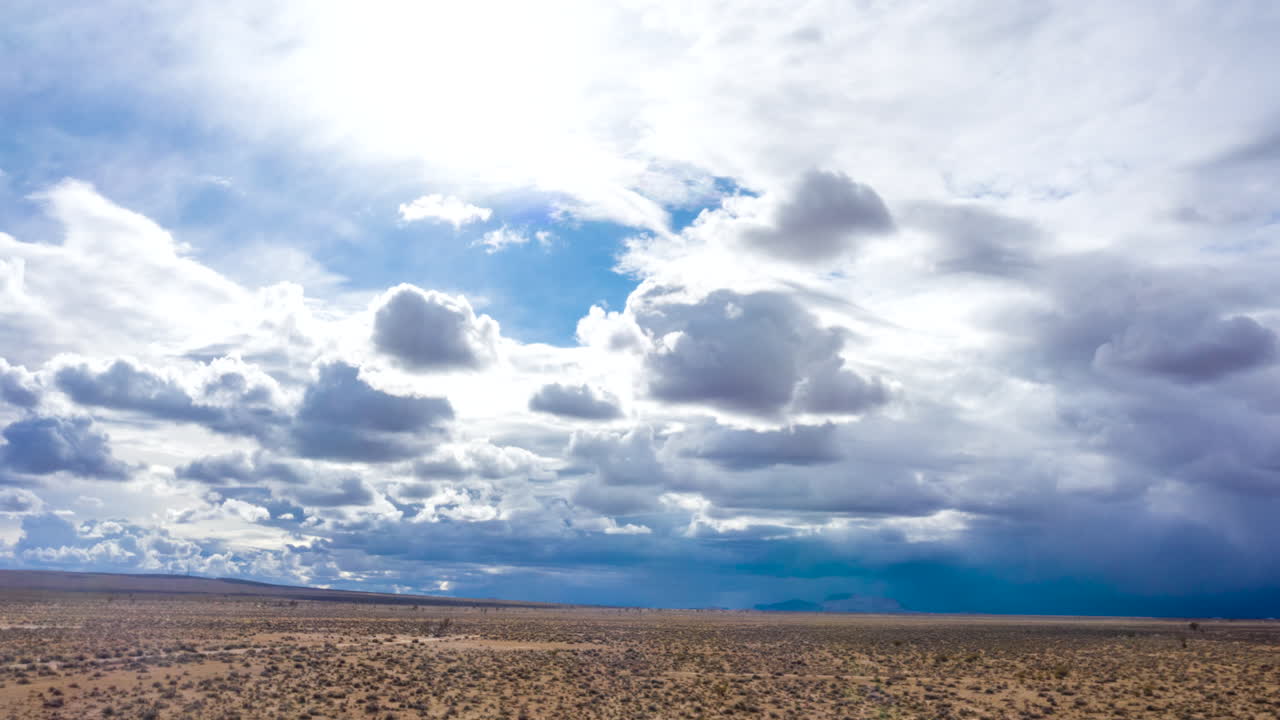volando sobre el desierto de mojave mientras se forman nubes de tormenta oscuras sobre la cabeza - hiperlapso aéreo