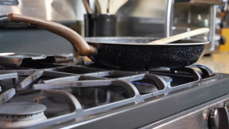 pan down focus of cooking pan on stove, blurred background of toaster and cooking utensils