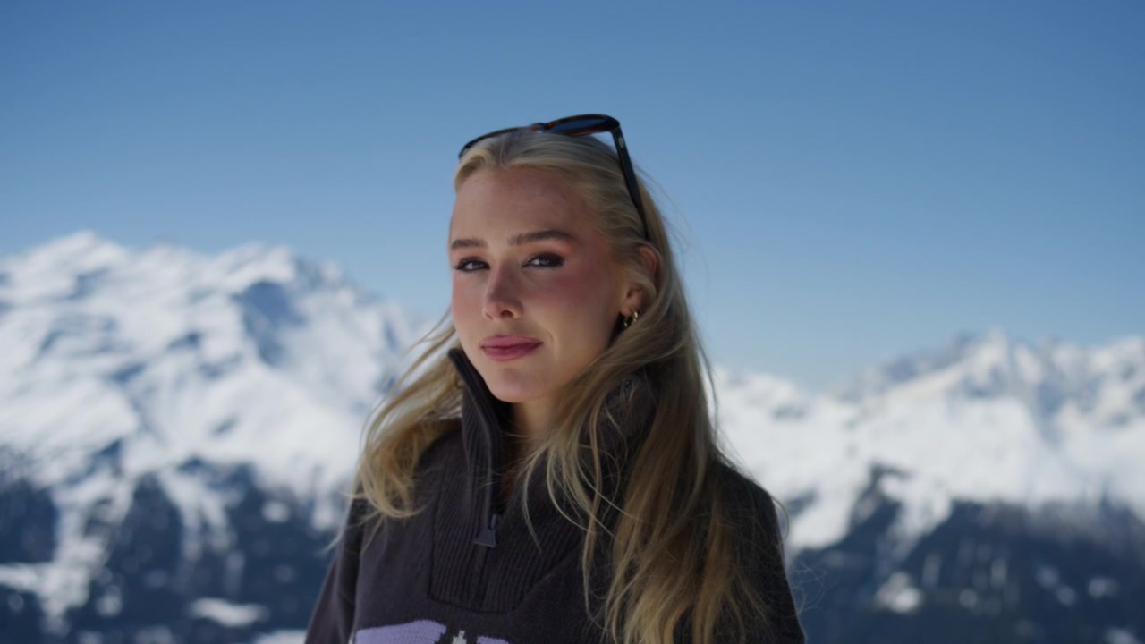 Ritratto ravvicinato di una giovane donna che si gode l'ambiente alpino a Verbier, Svizzera. Cime innevate e cieli azzurri e limpidi creano una scena di viaggio e stile di vita alpino di alta qualità nelle Alpi svizzere.