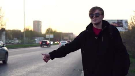 man waiting for a ride on the street at sunset