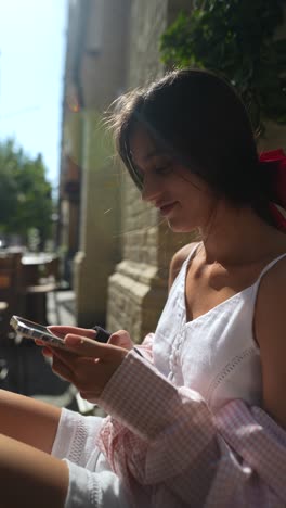 young woman using smartphone in outdoor cafe