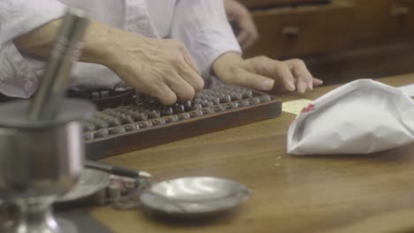 Static-shot-of-a-man-counting-on-a-abacus-known-as-the-suanpan-in-a-chinese-medicine-store,-inTaipei