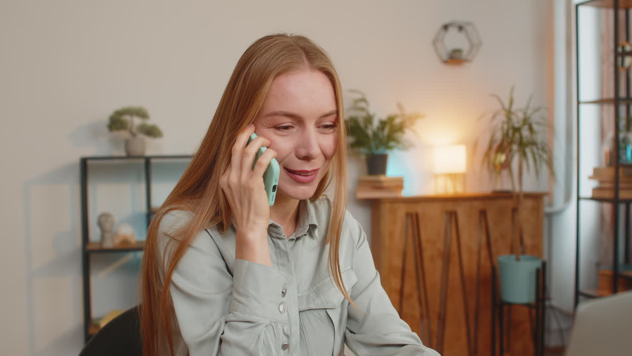 Confident caucasian mature businesswoman freelancer using smartphone and laptop at home office table