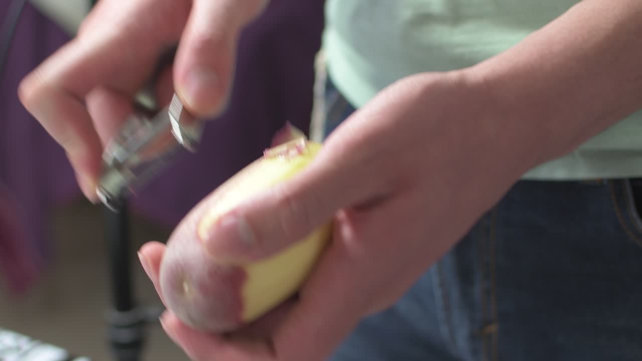 Close up of young man's hands peeling potatoes.