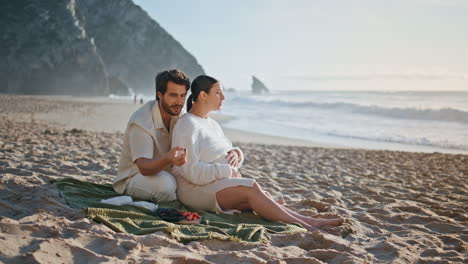 expectant parents enjoy picnic on sand beach summer evening. pregnant couple