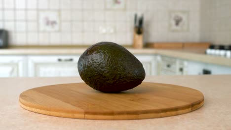 close up of fresh whole hass avocado. rotating camera with white kitchen on the background. dolly-shot.