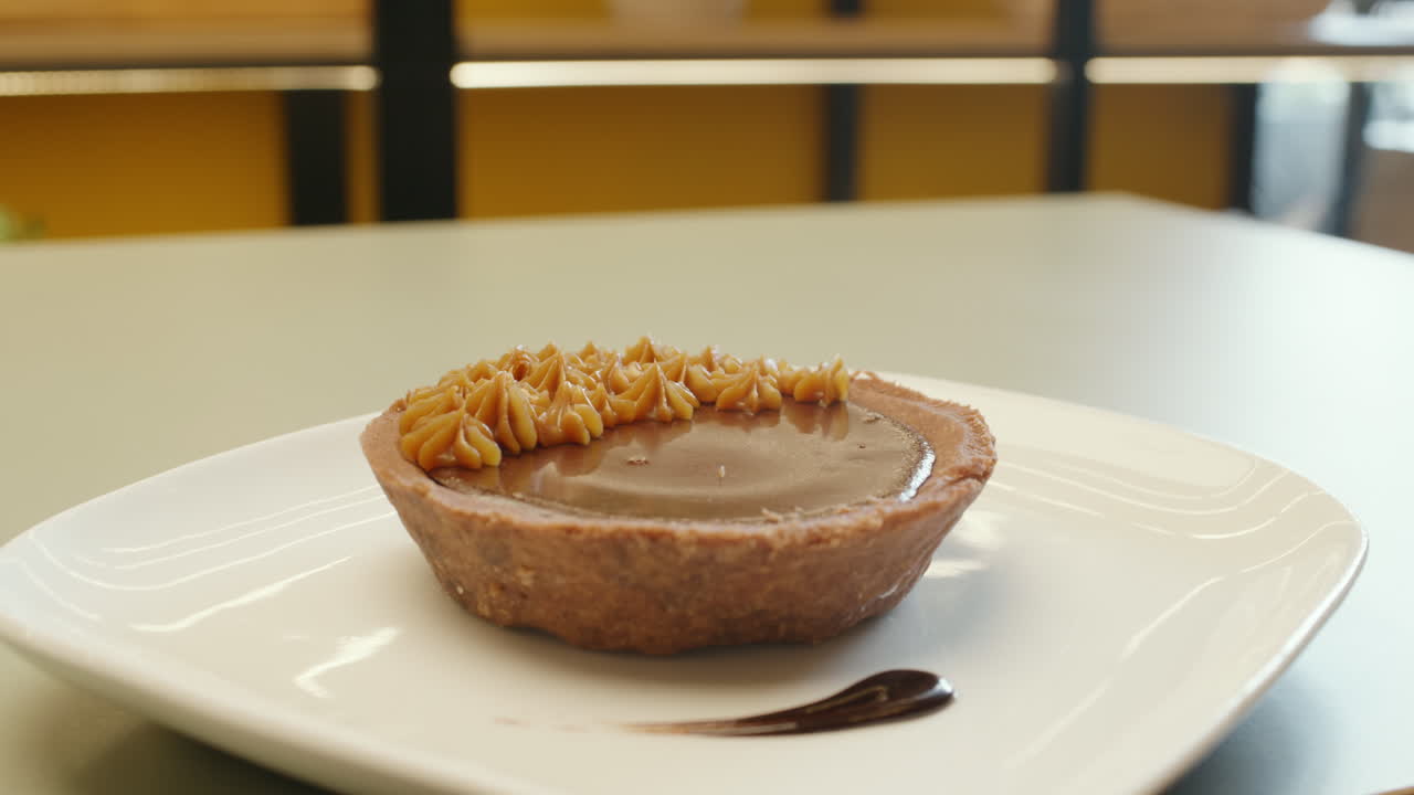 Panning shot of a chocolate cake adorned with fine peaks of dulce de leche, highlighting its texture and elegance