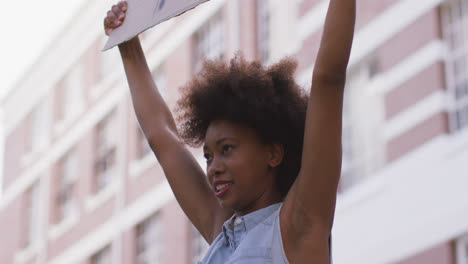 african american woman holding placard shouting during protest