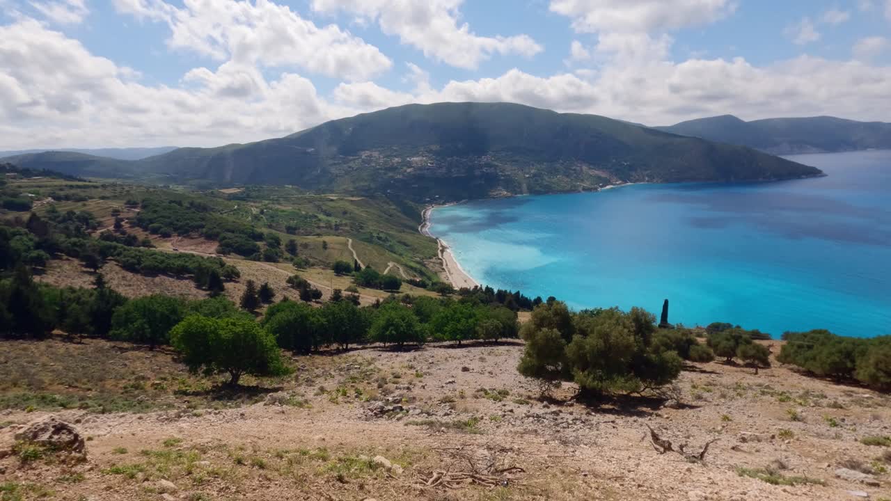 Stunning coastal viewpoint in Kefalonia, Greece, with vivid blue sea and dramatic mountains rising above Agia Eleni Beach—a hidden natural paradise.