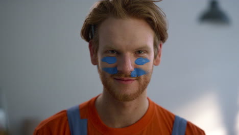 Cheerful-man-putting-war-paint-on-face-during-house-renovation-in-new-home.