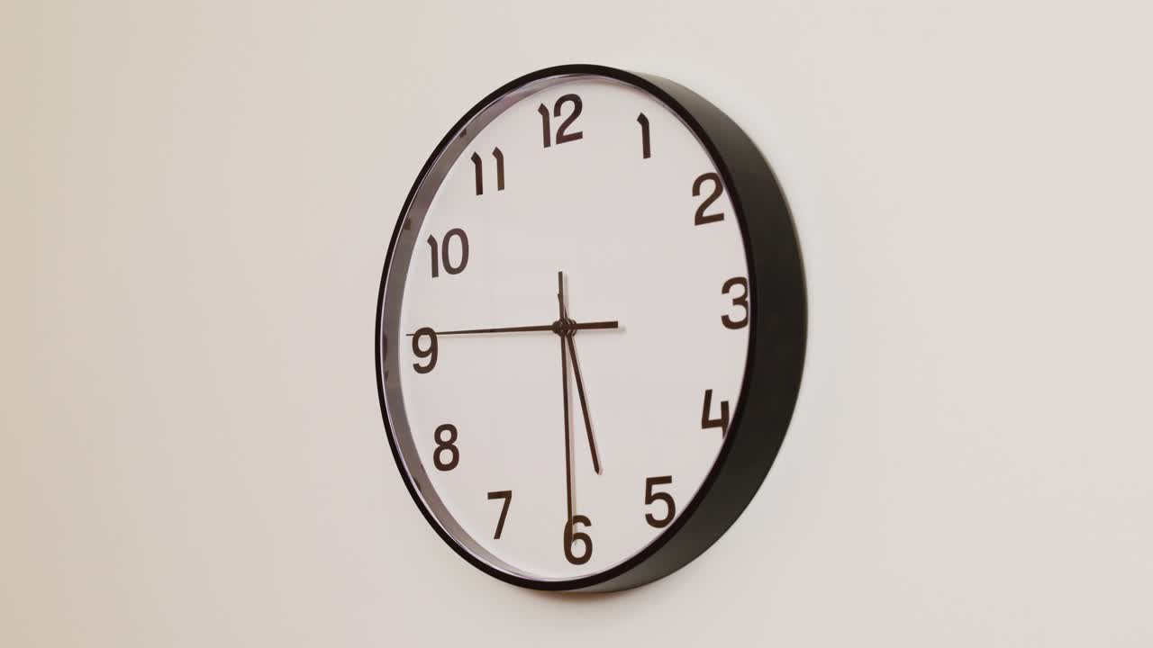 A detailed close-up of a wall clock with a black frame and white face, displaying the time at 5:30.