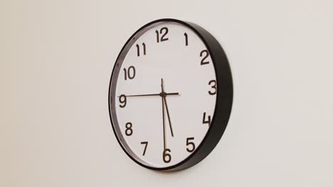 a detailed close-up of a wall clock with a black frame and white face, displaying the time at 5:30.